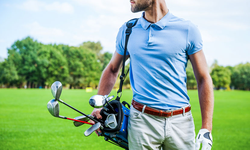 man wearing polo shirt carrying golf bag